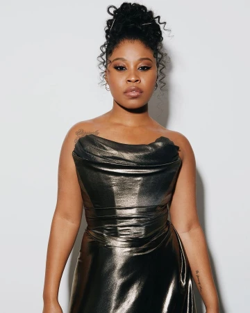 Black woman in a metallic strapless dress with hair in an updo against a white seamless background