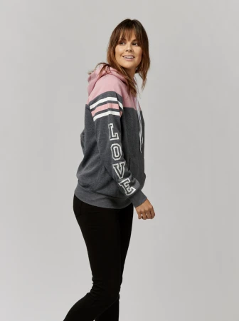 Attractive adult woman wearing a hooded sweatshirt with the word 'LOVE' printed on the sleeve poses in a studio setting.
