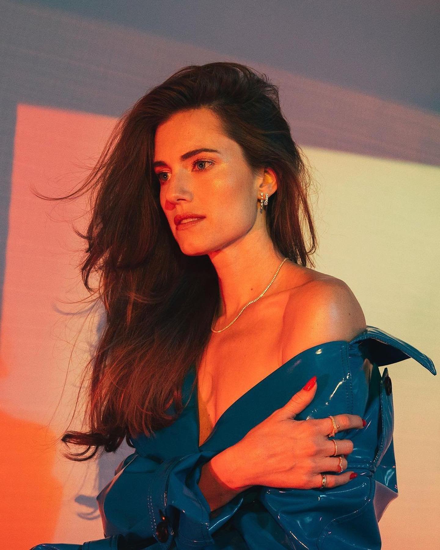 Portrait of a brunette woman with a blue top looking off-camera, with dramatic lighting and a clean background. Fashion, beauty.