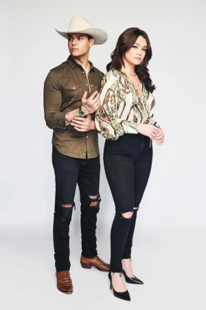 Man in cowboy hat and woman in patterned blouse standing against a white seamless background