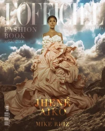 Jhene Aiko posing in a large ruffled peach gown against a dramatic rocky mountain landscape and cloudy sky background