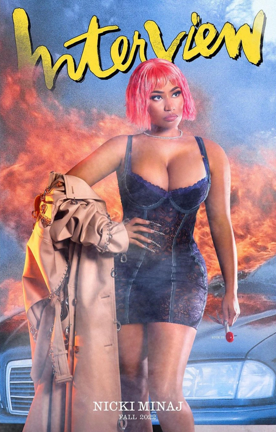 Nicki Minaj with pink bob hair wearing a lace corset and trench coat with nail art by Yvett G in front of a burning car