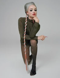 Woman with silver hair and long braided extension kneeling on a white seamless background wearing a high neck metallic top and patterned tights