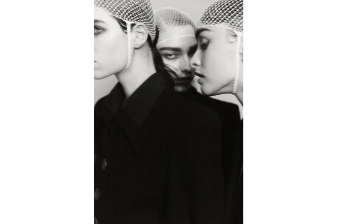Three models wearing mesh head coverings and dark jackets in a black and white portrait by Daniel Goode