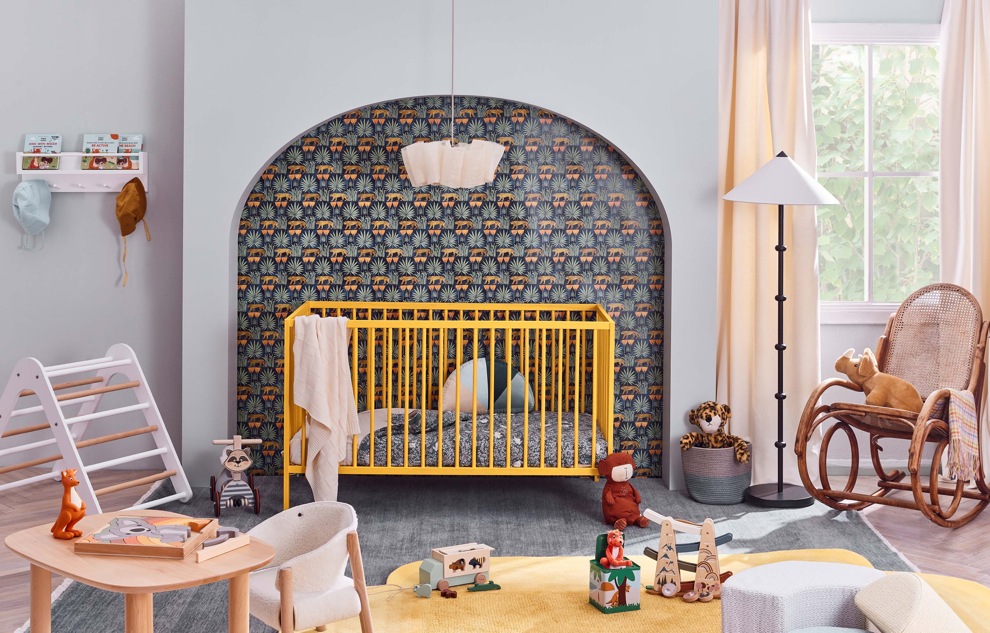 Bright, inviting nursery interior with a yellow crib, wooden toys, rocking chair, patterned wallpaper, and soft natural light.