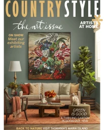 Magazine cover featuring a living room with a beige sofa, floral artwork, potted fiddle-leaf fig, and a cat on a stool.
