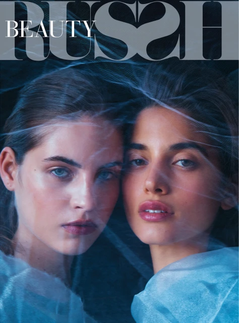 Beauty editorial featuring two adult women closely posed under a veil, bathed in blue lighting, conveying a sophisticated and ethereal aesthetic.