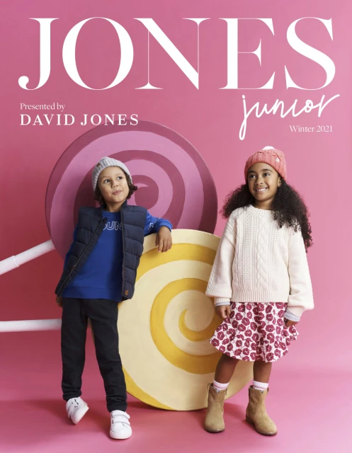 Fashion ad for David Jones Junior Winter 2021 featuring two kids in winter clothing standing in front of oversized candy props.