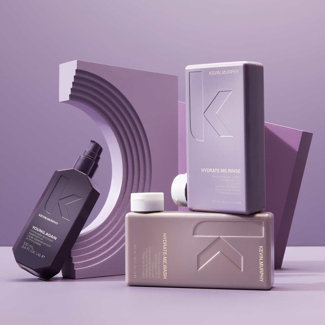 Three bottles of Kevin Murphy hair products are arranged in front of an architectural backdrop, creating a minimalist beauty product shot.