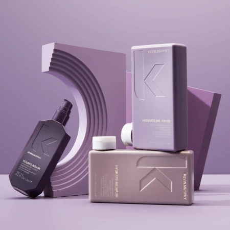 Three bottles of Kevin Murphy hair products are arranged in front of an architectural backdrop, creating a minimalist beauty product shot.