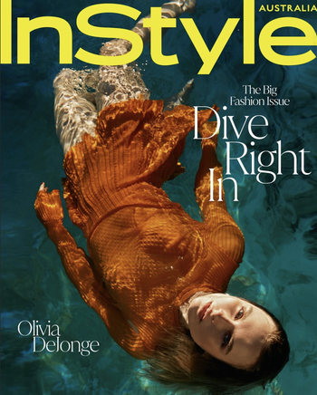 Woman wearing an orange dress submerged underwater in a swimming pool, photographed from above by Sylve Colless.