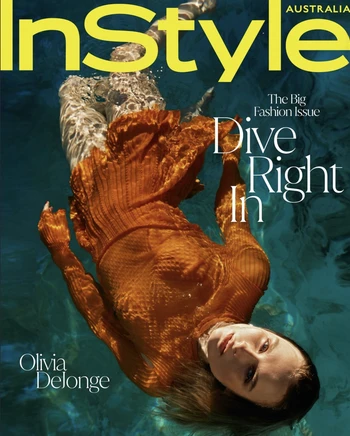 Woman wearing an orange dress submerged underwater in a swimming pool, photographed from above by Sylve Colless.