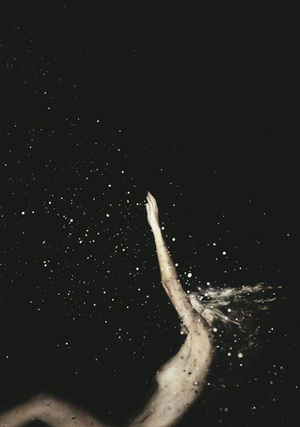 A woman with fair skin and blonde hair raises her arm in front of a dark, cosmic background with glittering bokeh lights.