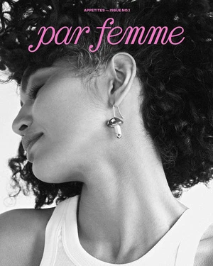 Black and white portrait of a woman wearing a mushroom earring and a white tank top by Sylve Colless