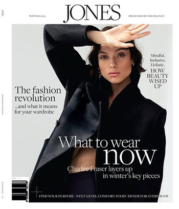 Fashion magazine cover featuring a young woman in a dark coat, shielding her eyes with her hand, with magazine text and branding.