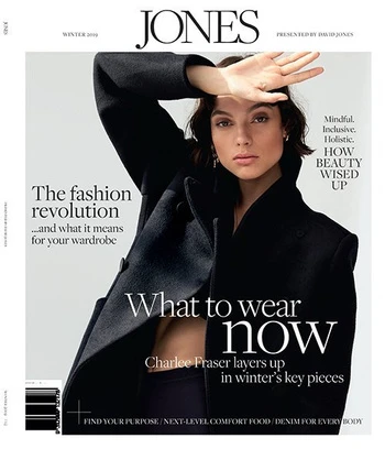 Fashion magazine cover featuring a young woman in a dark coat, shielding her eyes with her hand, with magazine text and branding.
