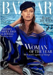 Female model in a vibrant blue off-shoulder top and striped trousers sitting outdoors by water for a magazine cover shot.