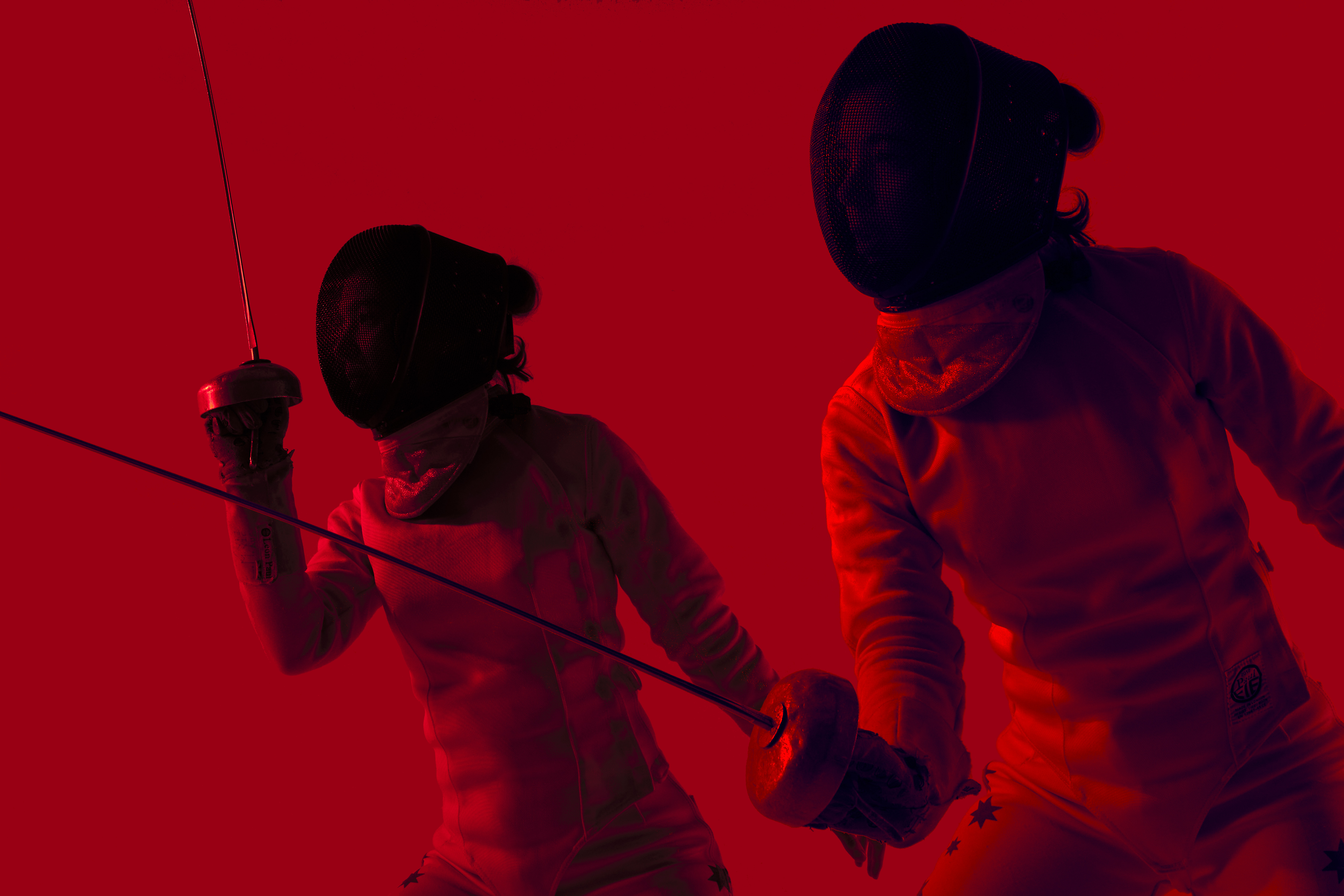 Two fencers in protective gear face each other with foils raised in a red-toned image, highlighting the intensity of the sport.