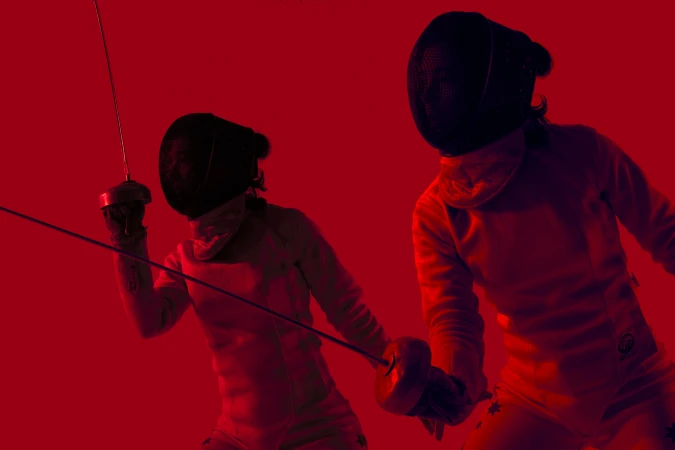Two fencers in protective gear face each other with foils raised in a red-toned image, highlighting the intensity of the sport.