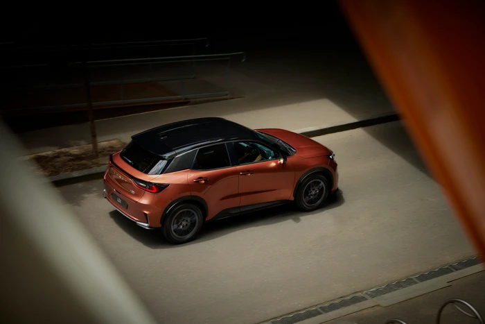 High angle shot of a copper and black crossover SUV on an urban paved road lit with warm spotlighting.
