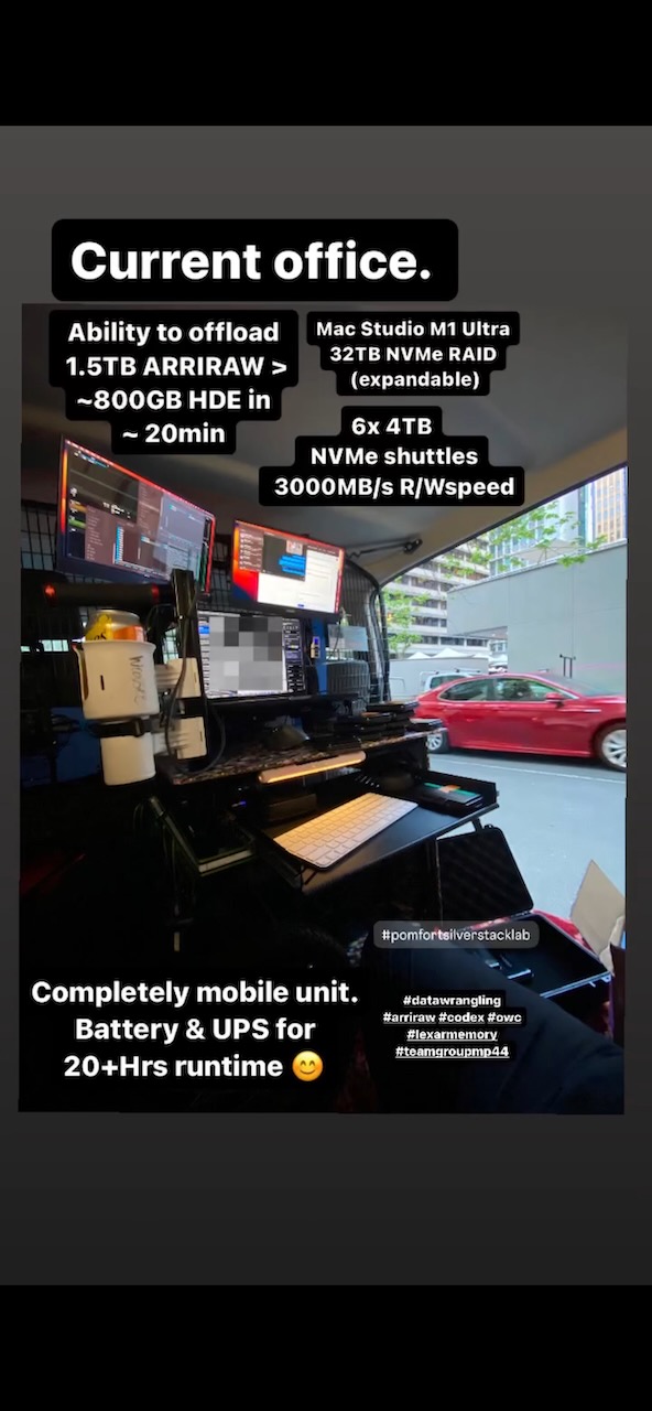 Mobile workstation in van with monitors, Mac Studio, and battery/UPS setup for on-location video editing, with a red car visible outside.