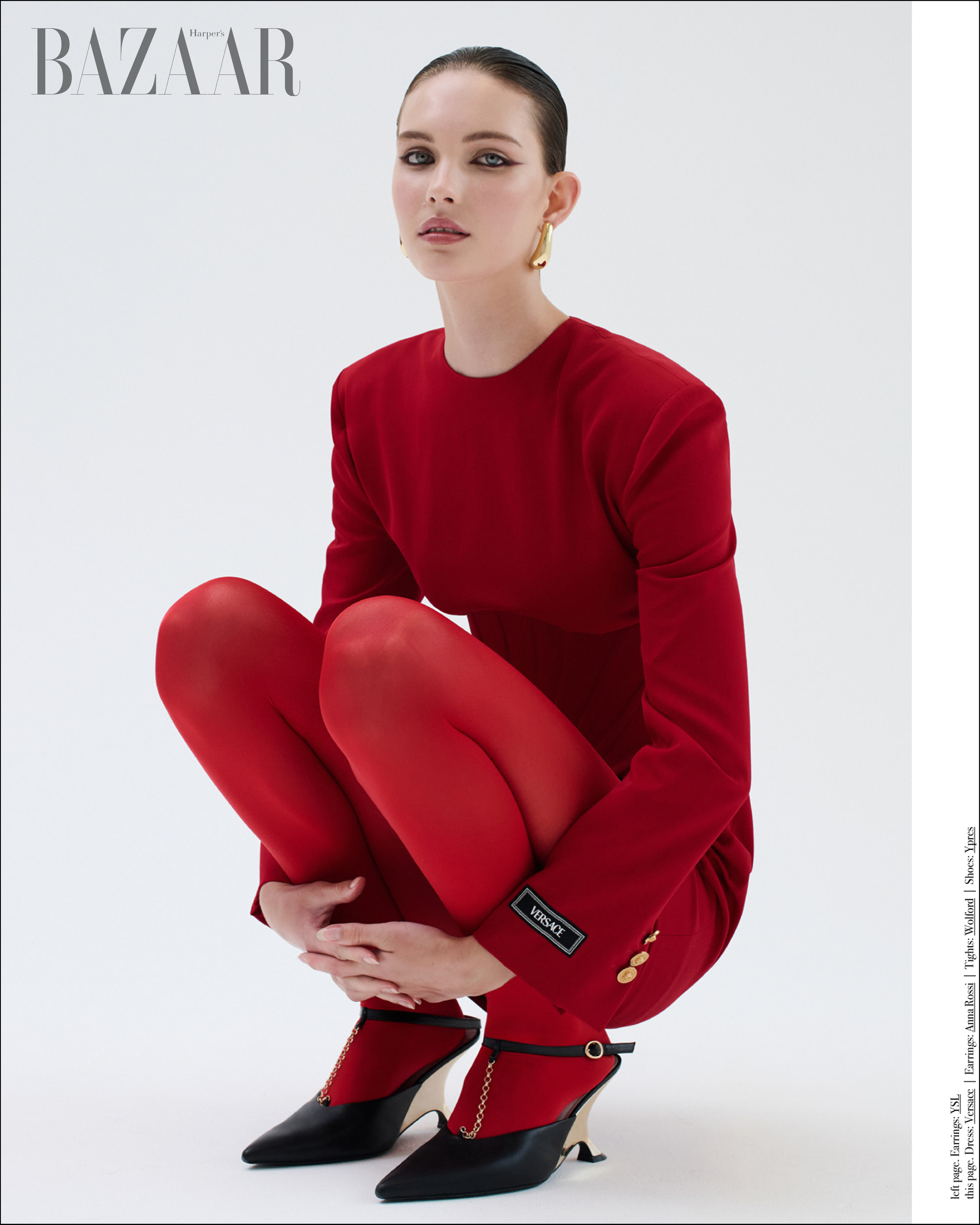 A young woman in a red blazer, red tights, and black high heels poses against a white backdrop in a fashion editorial shot.