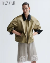 Model wearing a tan jacket with black collar and patterned shorts against a white backdrop styled by Léa Phillips