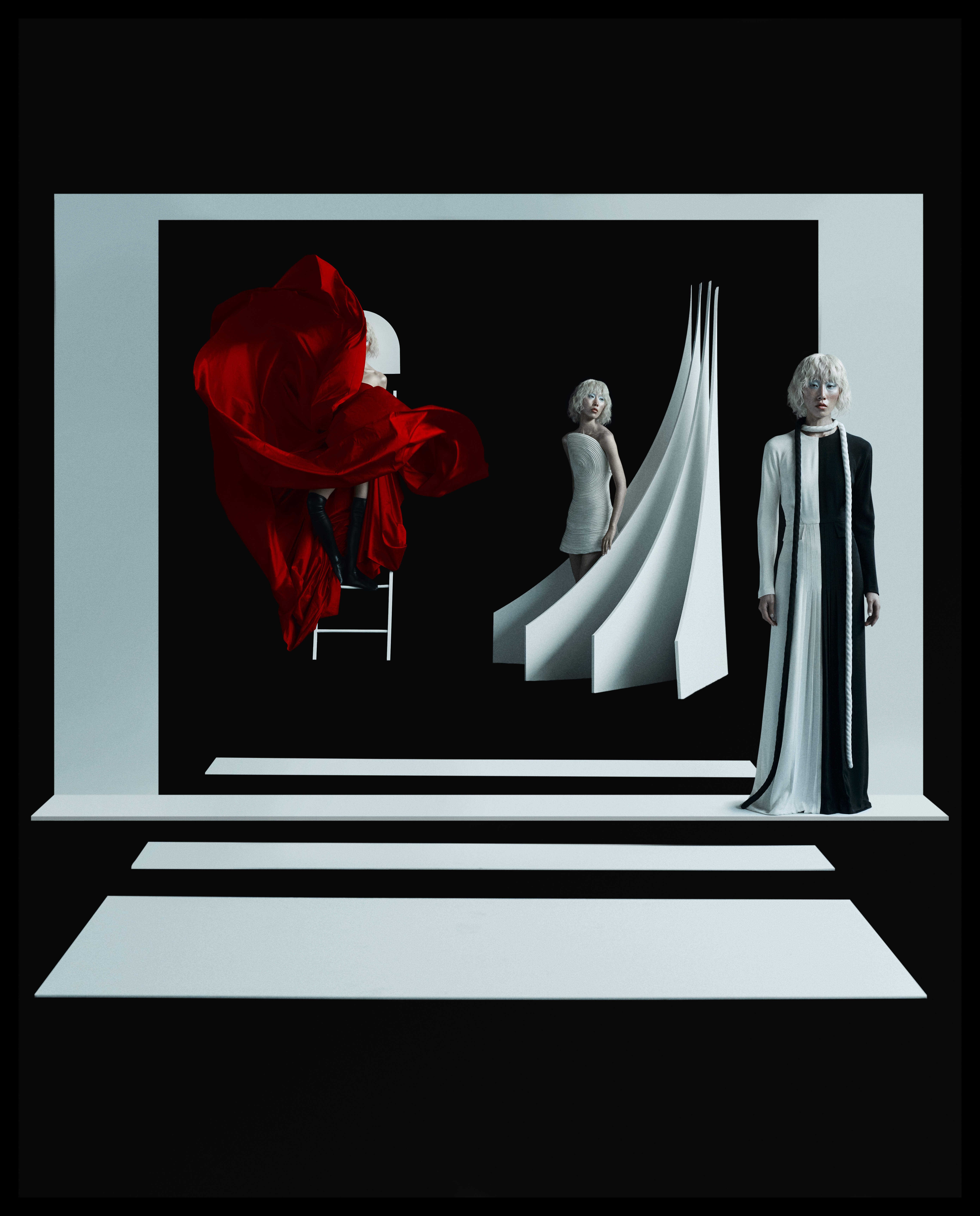 Three fashion models in conceptual dresses strike poses in a staged photo studio with minimalist white geometric platforms.