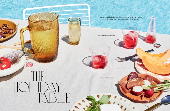 Outdoor holiday table scene featuring a pitcher, glasses, plates of snacks, and text overlay, all arranged on a linen tablecloth.