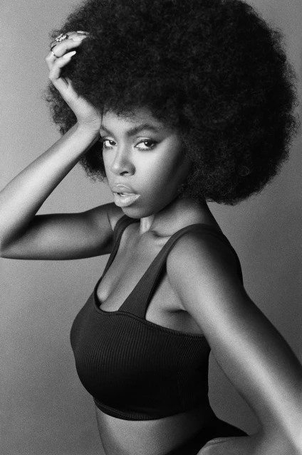 Black and white portrait of an African American woman with a large afro wearing a ribbed crop top in a studio setting.