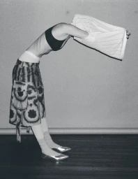 Model bending backward wearing a patterned skirt and silver shoes, photographed by Seung Rok in black and white.