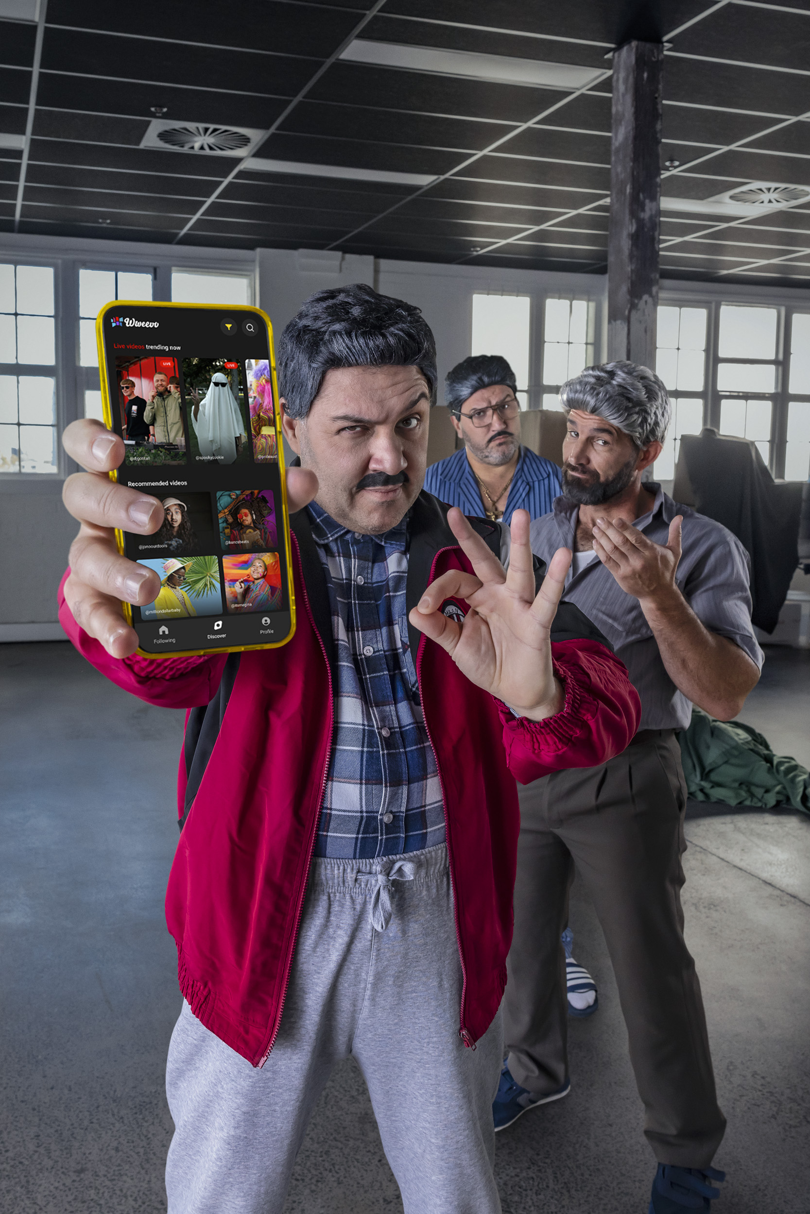 Three adult males display a smartphone showing the Visie platform against a background of an open workspace with visible ceiling pipes.
