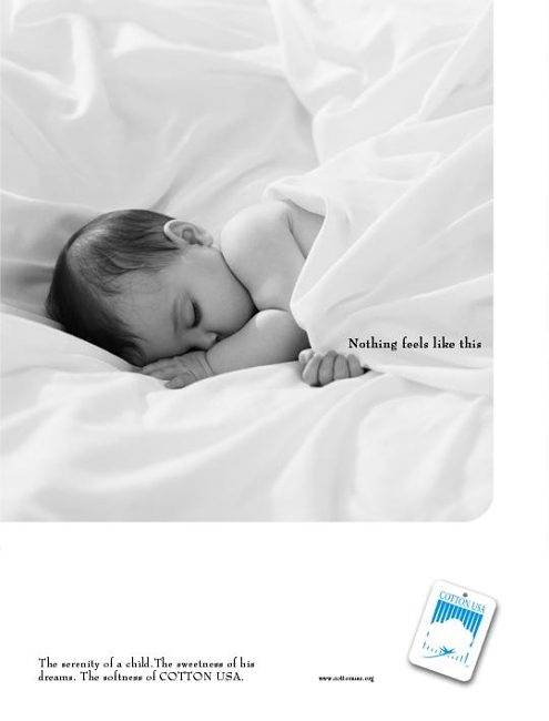 Infant sleeping peacefully in white bedsheets, bathed in soft, diffused lighting, conveying serenity and comfort with focus on cotton quality.