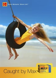 A young girl with long blonde hair smiling while swinging on a tire swing over a sandy beach against a blue sky.