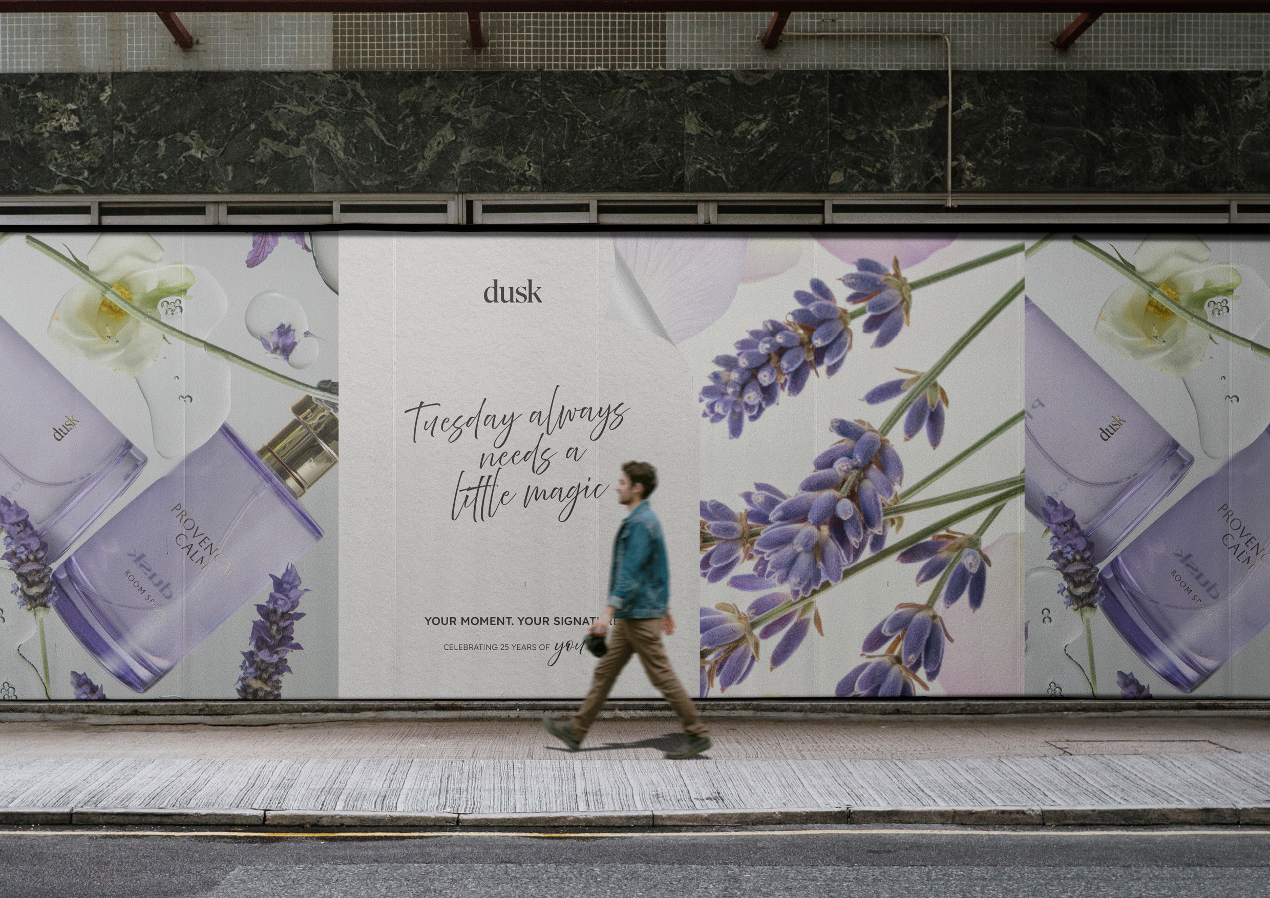 Advertising billboard with a cologne bottle, lavender, and flowers, featuring an adult male in motion on an urban sidewalk.