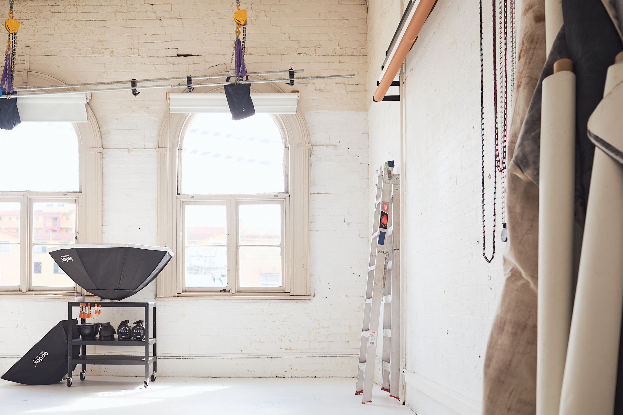 Bright photography studio interior with softboxes, stands, white walls, and backdrop rolls creating a professional creative space.