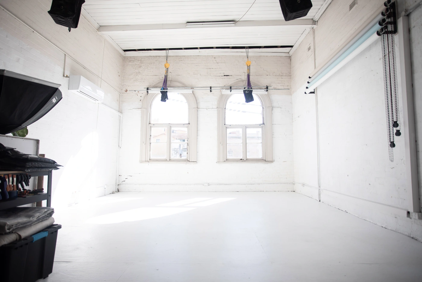 Empty white photography studio interior with arched windows and lighting equipment by Desk and Studio in Sydney