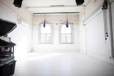 Empty white photography studio interior with arched windows and lighting equipment by Desk and Studio in Sydney