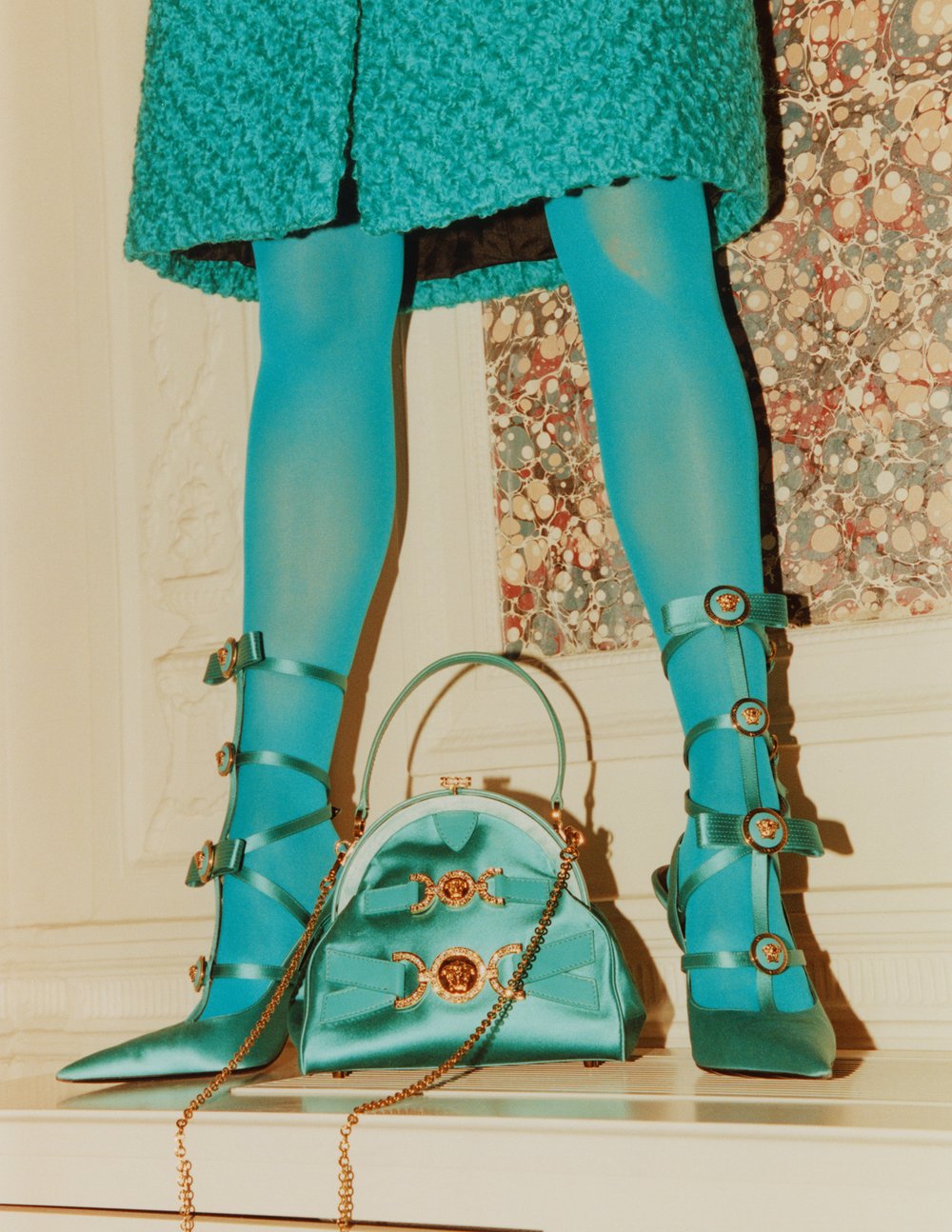 Close-up of woman's legs in blue tights and heels with matching purse; fashion, style, luxury accessories, studio shot.