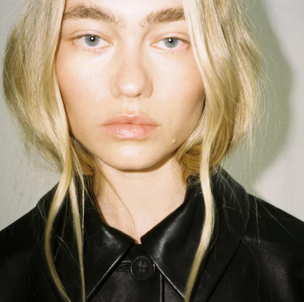 Close-up portrait of a young woman with blonde hair and black leather jacket. Beauty shot of fair-skinned woman with neutral expression.