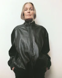 Mature woman wearing a black leather zip-up jacket against a plain white background