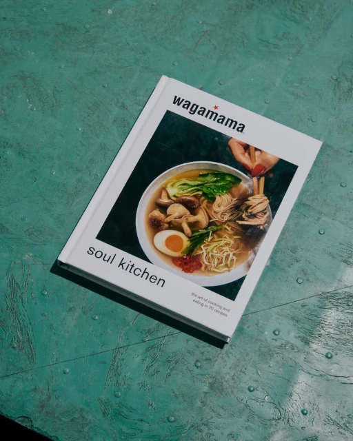Wagamama cookbook, 'Soul Kitchen', features a bowl of ramen noodles with egg, greens, and mushrooms on a textured green surface.