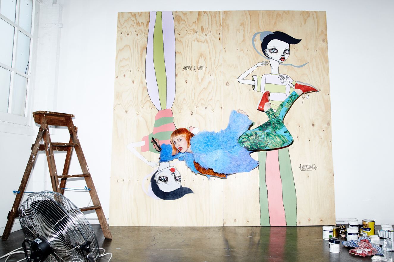 Illustration of woman combined with a real woman lying on a wooden board, next to a vintage fan and stepladder in a white studio.