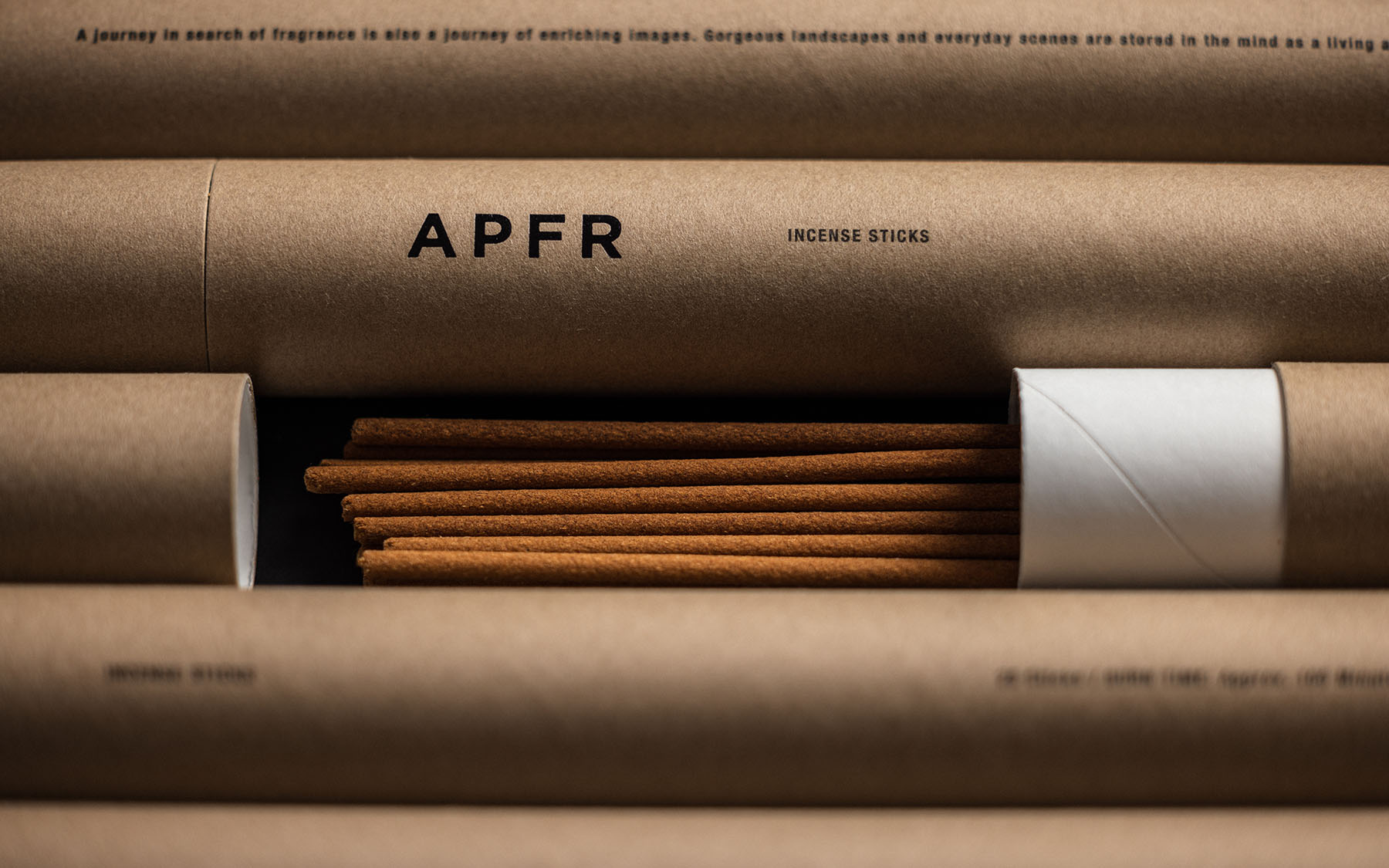 Close-up product shot of a collection of APFR incense sticks in brown paper tubes with visible label text, arranged indoors.