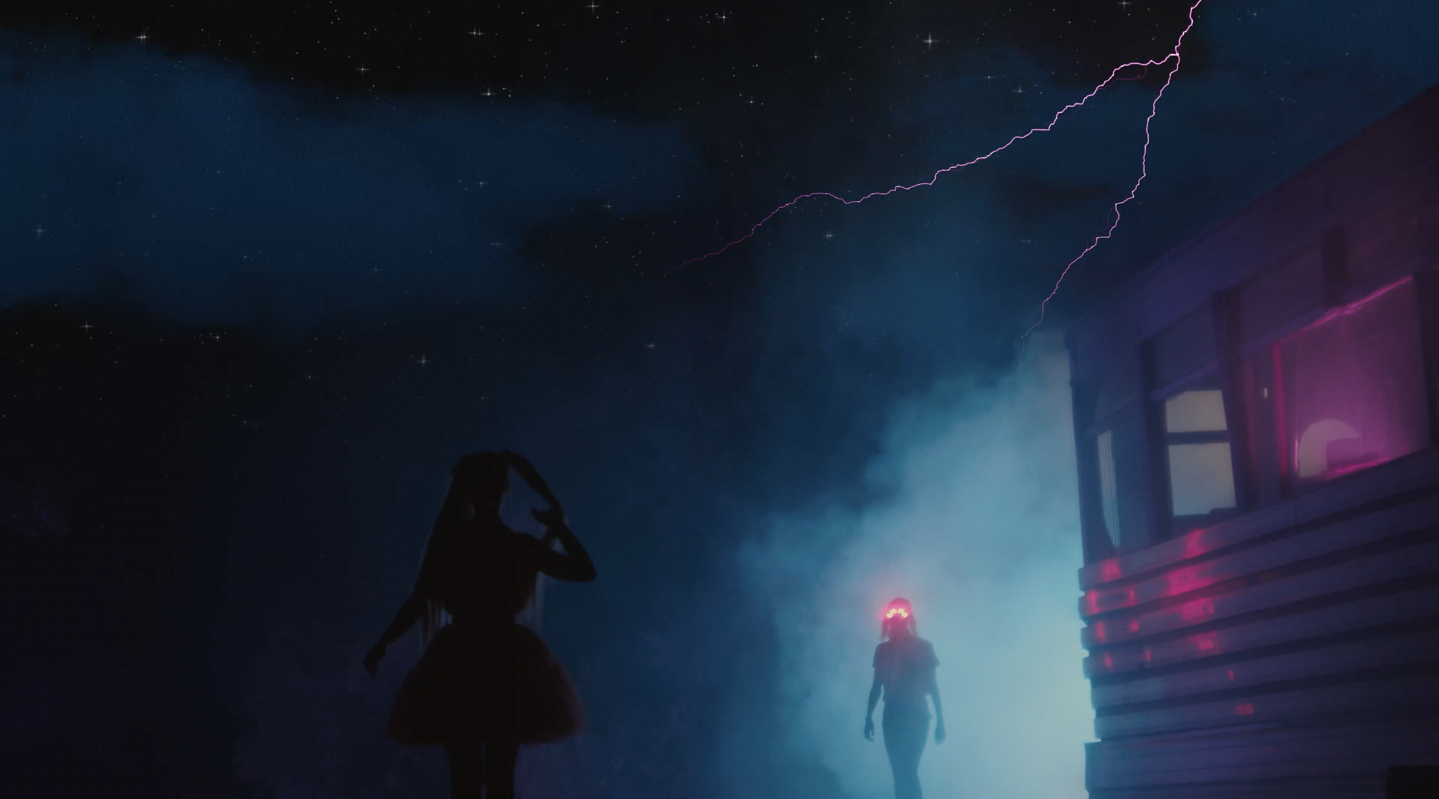 Two figures stand near a building under a night sky with lightning. One woman is silhouetted while the other stands in the doorway of a building.