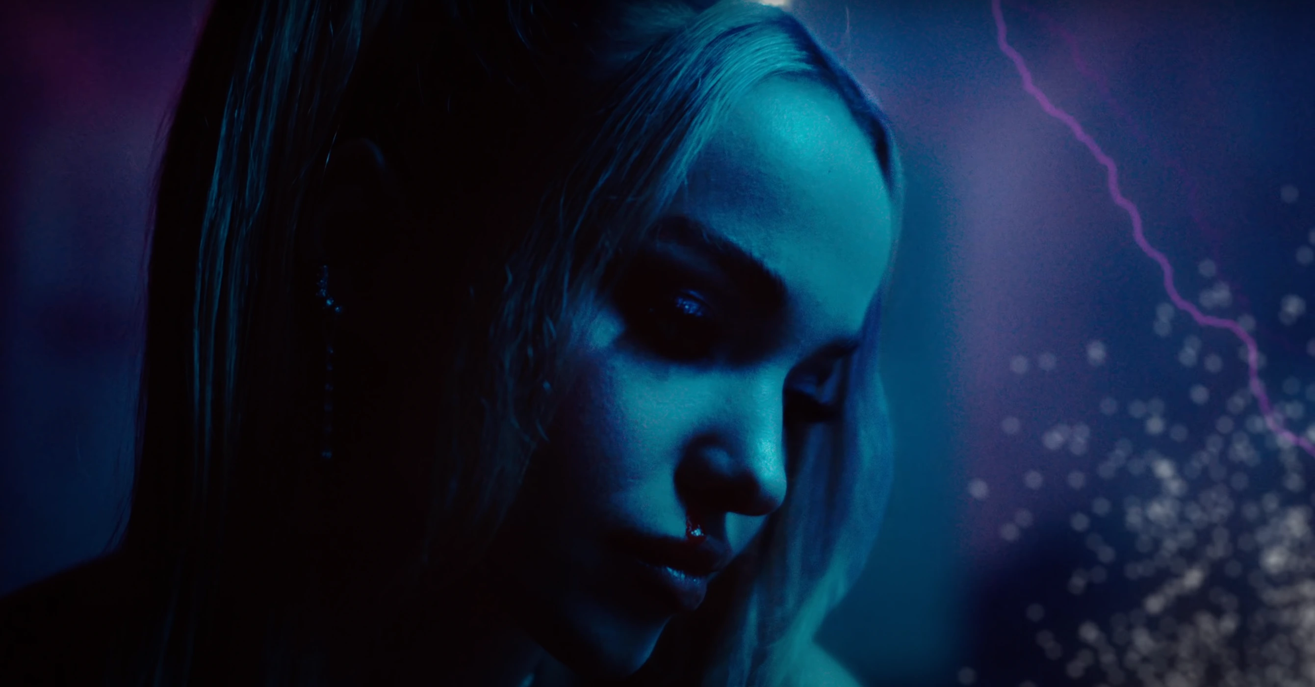 Close-up profile of a woman with blonde hair in dramatic blue and purple neon lighting with glowing particle effects.