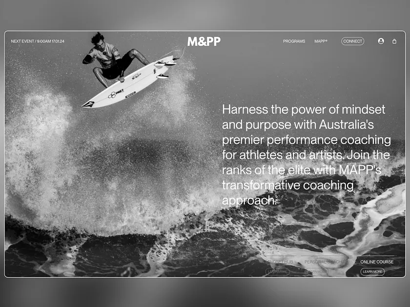 A surfer performs a trick on a surfboard above a large wave in this monochrome website hero image. Surfer is airborne and silhouetted.