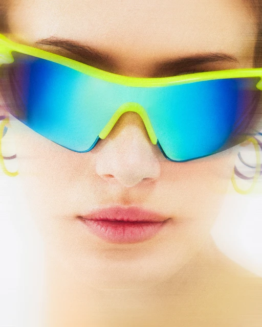 Close-up of a fair-skinned woman wearing vivid neon-yellow framed sunglasses with blue mirrored lenses against a white background.