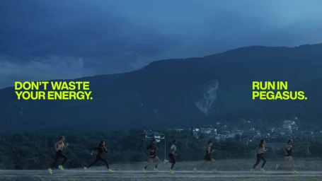 A group of runners on a road at dusk with mountains in the background and bold yellow text on both sides