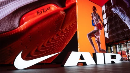 Giant digital screens and illuminated Nike Air logos display a basketball player and shoe details in a large commercial interior.